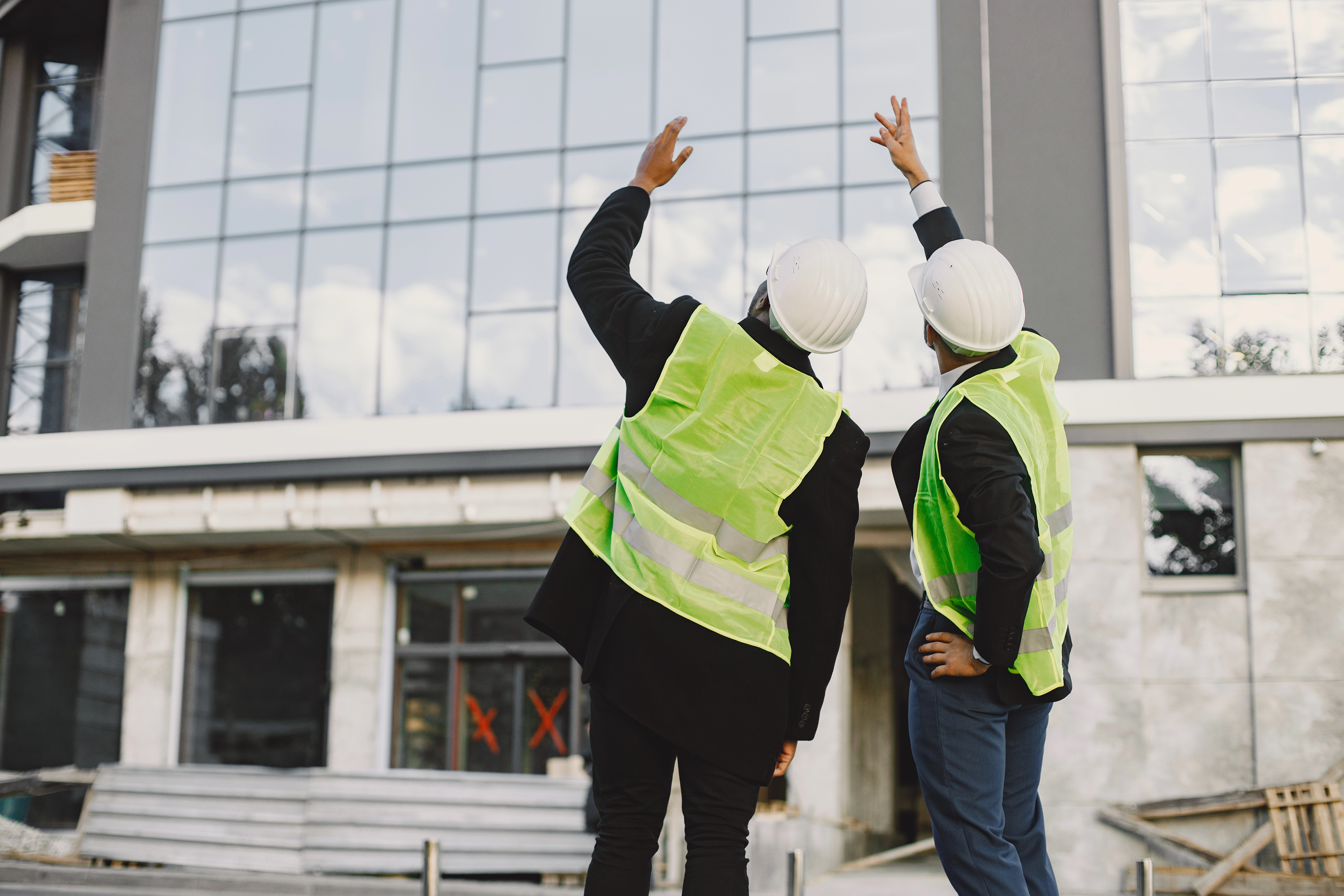 Multi Racial Builders Standing Outdoors Back View Wearing Uniform Talking About New Glass Building Working Poject City Infrastructure