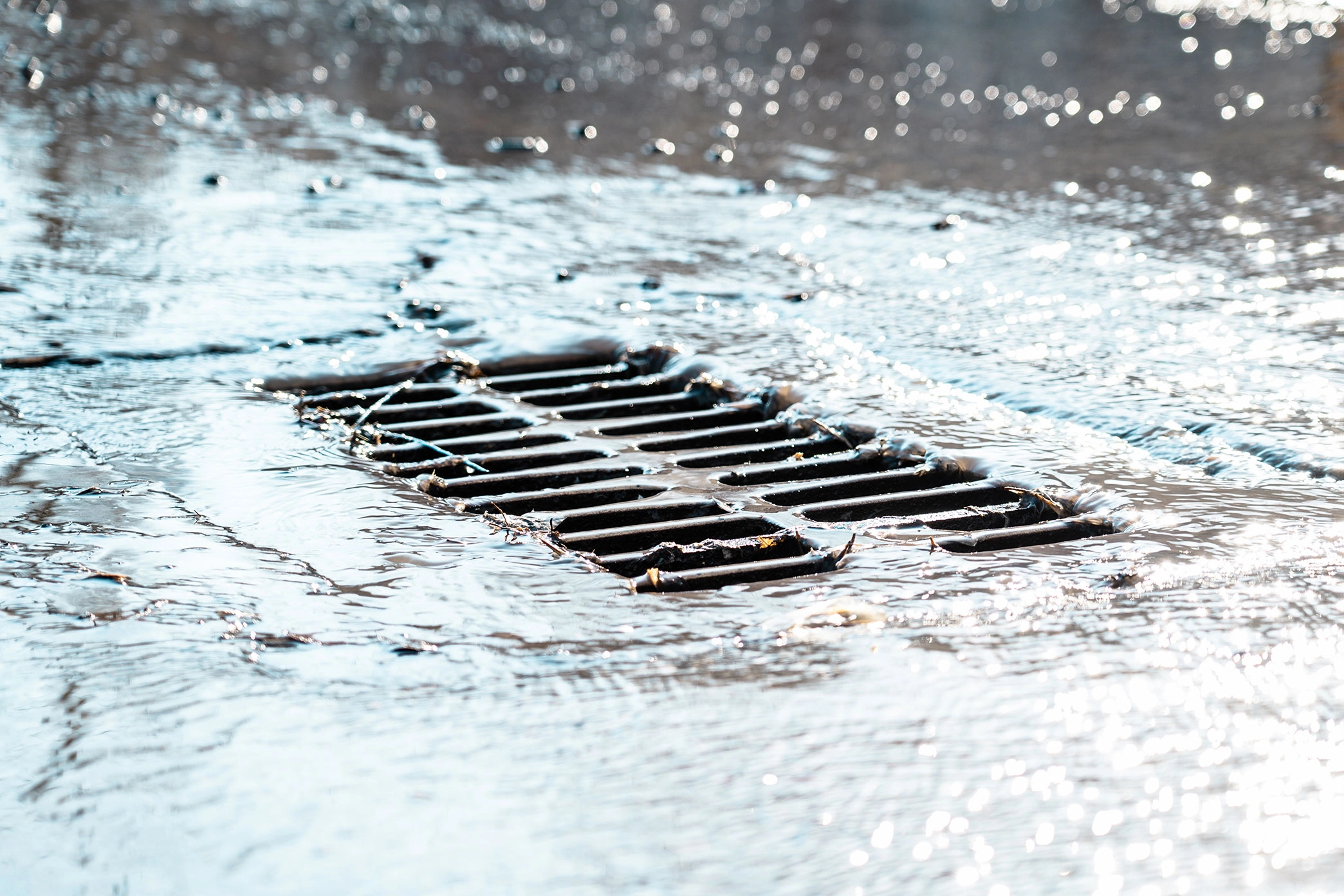 Grate Storm Sewer After Rain Water Drains Into Storm Drain Sun Glare Defocused Background 2