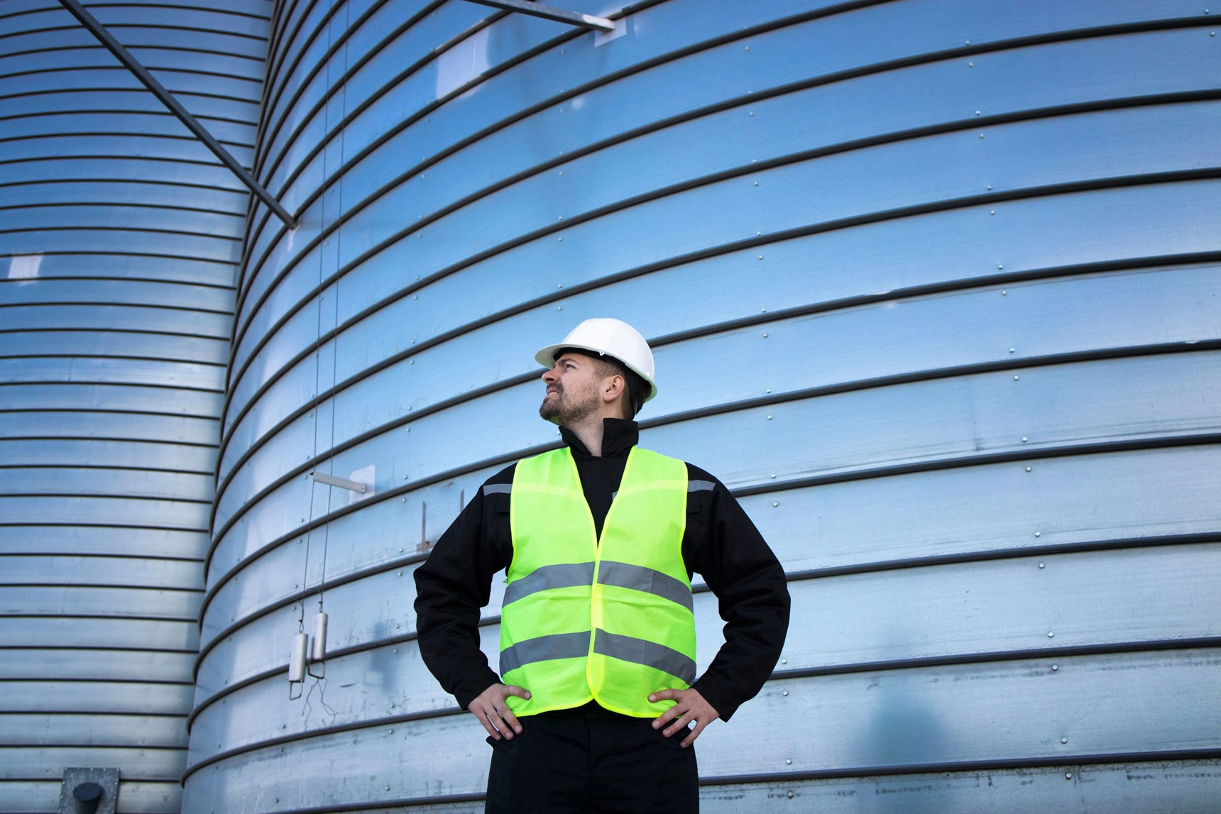 Portrait Industrial Worker Standing By Metal Silo Storage Tank 2