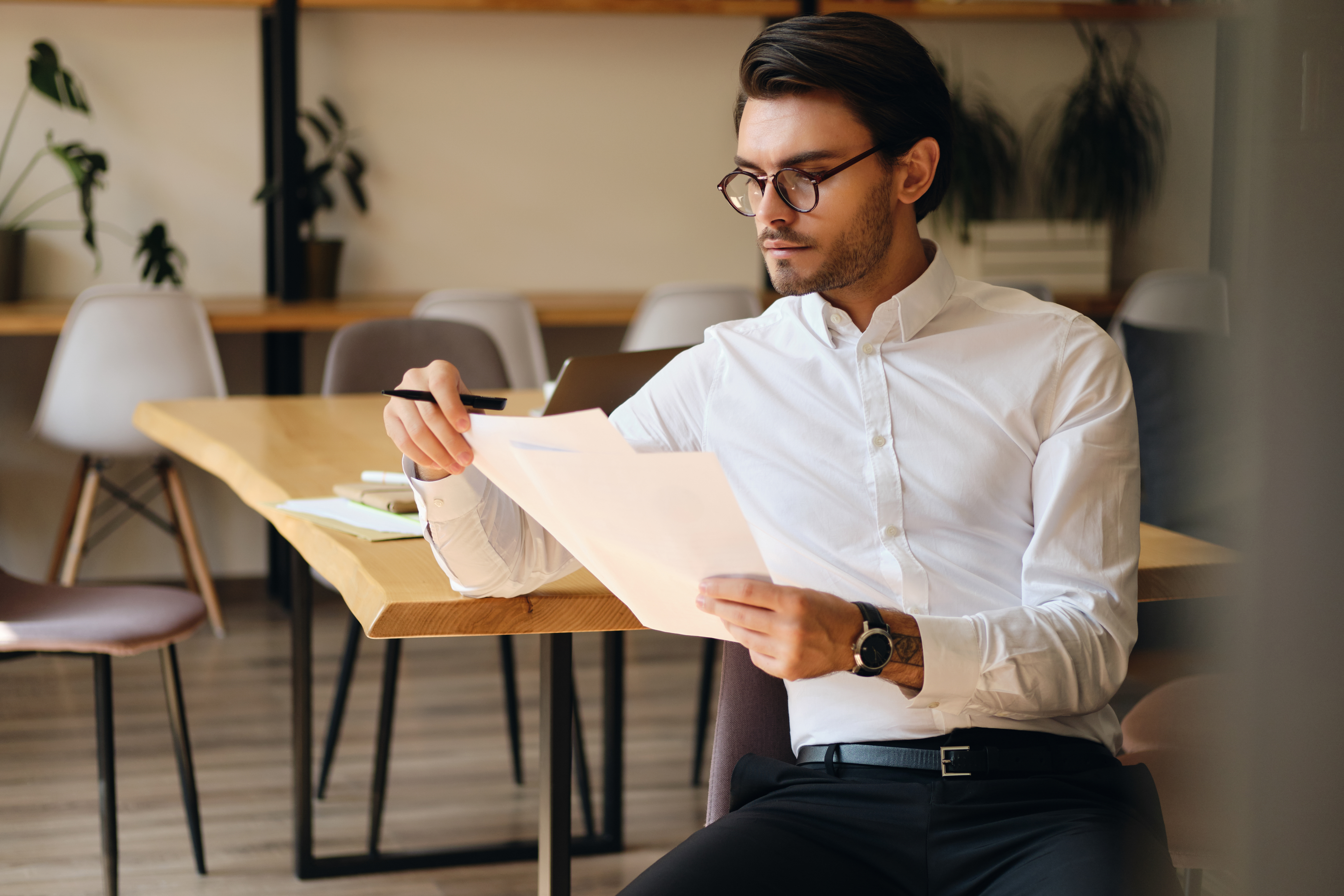 Young Serious Businessman Eyeglasses Thoughtfully Working With Papers Modern Office